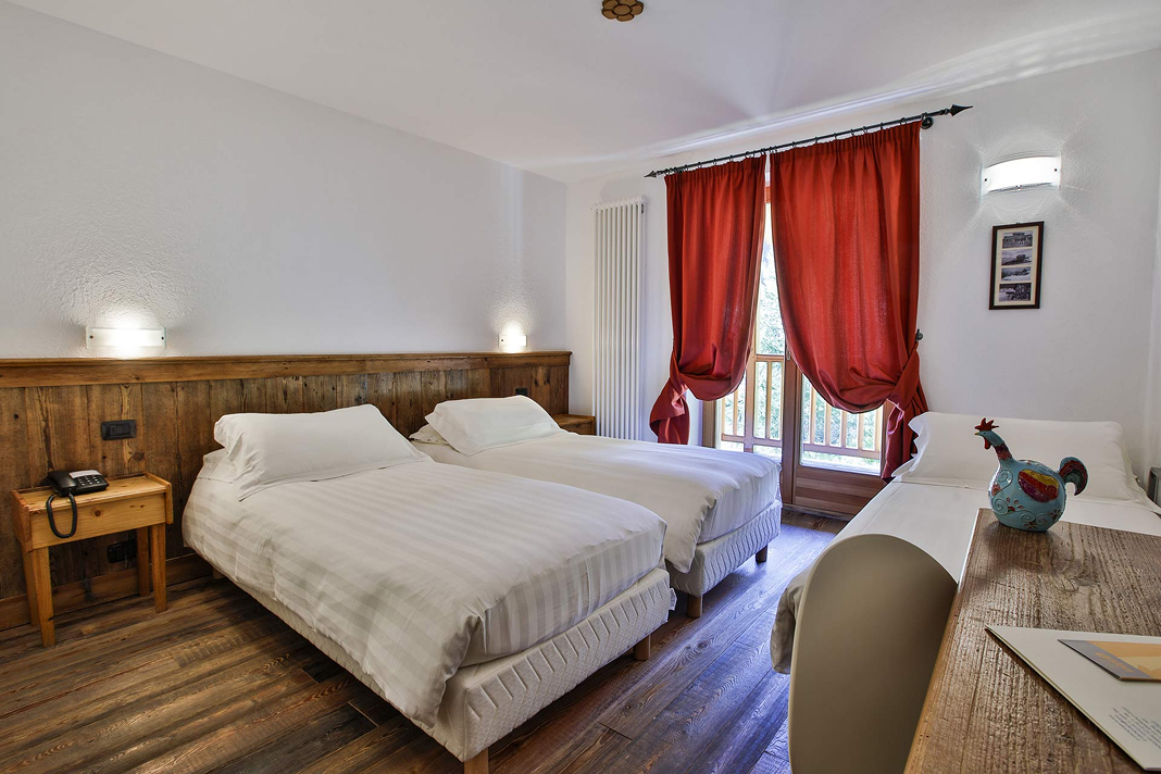 Camera Doppia con letto aggiunto: due letti affiancati, letto singolo e tende rosse