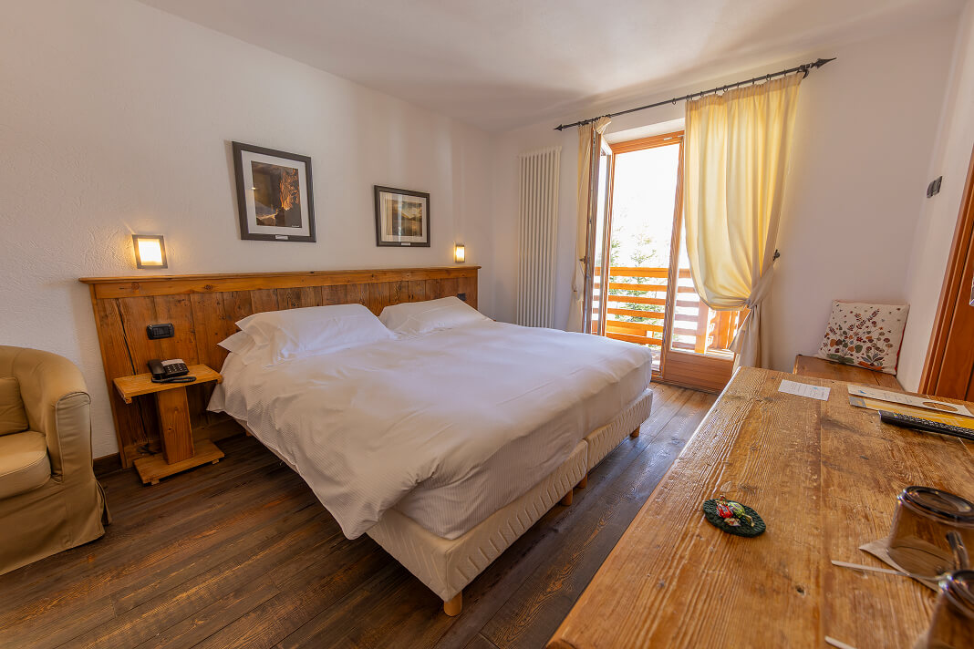 Camera Doppia con letto matrimoniale, testiera in legno e portafinestra sul balcone