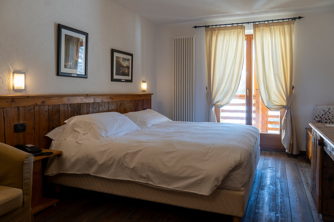 Camera Doppia Eco con letto matrimoniale, arredi in legno e tende chiare
