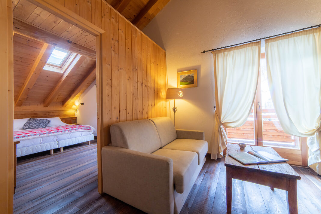 Suite con salotto, divano e camera da letto rivestita in legno